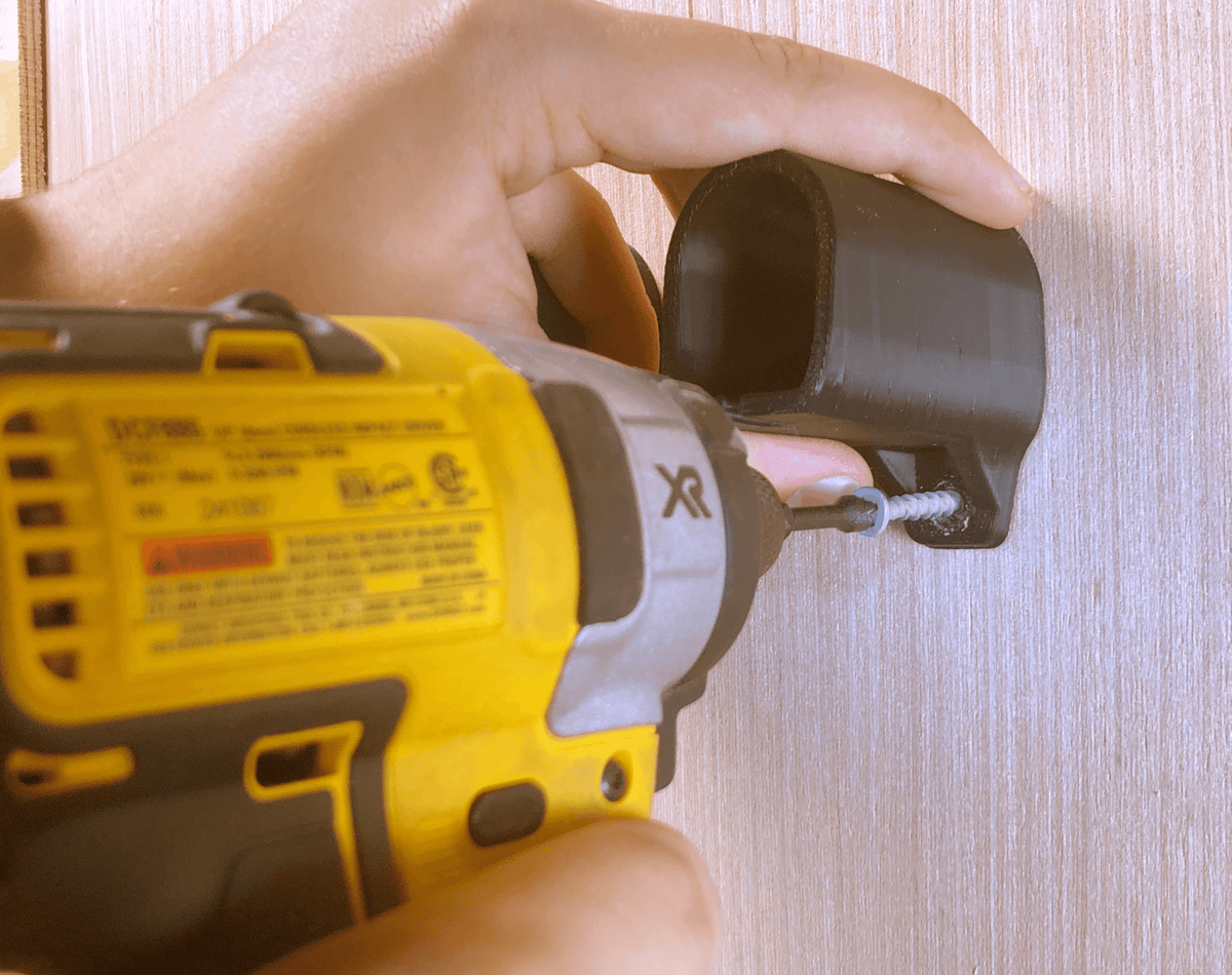 Installing a black battery wall mount with a drill; screws and tools are not included.